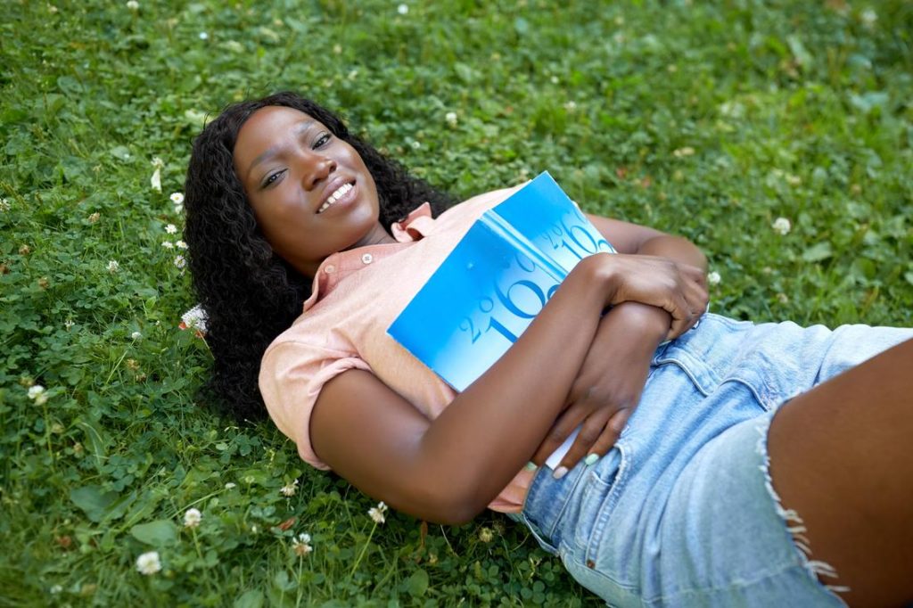 young lady relaxing with a book in nature to reduce stress